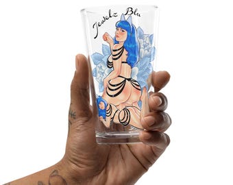 May include: A clear glass with a blue and black illustration of a woman with blue hair and a cat ear headband. The text "Jewelz Blu" is printed on the glass.