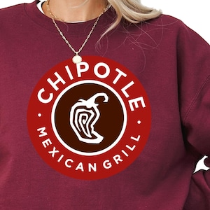 May include: Burgundy crewneck sweatshirt with the Chipotle Mexican Grill logo in a circular design. The logo features a stylized pepper graphic. The sweatshirt is paired with black shorts and a white undershirt.