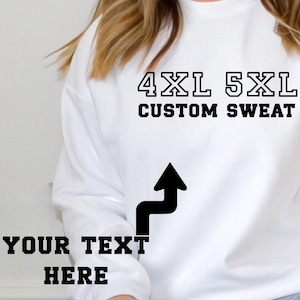 May include: A white sweatshirt with the text "4XL 5XL CUSTOM SWEAT" in black block letters. Below the text is a black arrow pointing towards the words "YOUR TEXT HERE" in black block letters. The sweatshirt is plain and has long sleeves.