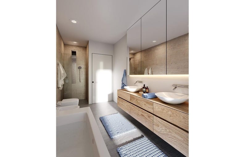 May include: A modern bathroom featuring a floating light wood vanity with two white vessel sinks, a large wall-to-wall mirror with under-cabinet lighting, a white bathtub, a walk-in shower, and two blue textured bath mats on the floor.