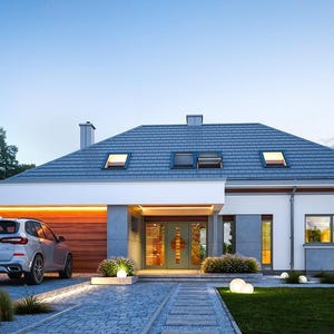May include: A modern one-story house with a gray tiled roof, white exterior walls, and gray stone accents. A silver SUV is parked in the driveway next to a wooden garage door. The entrance features a glass door, and the front yard has small shrubs.
