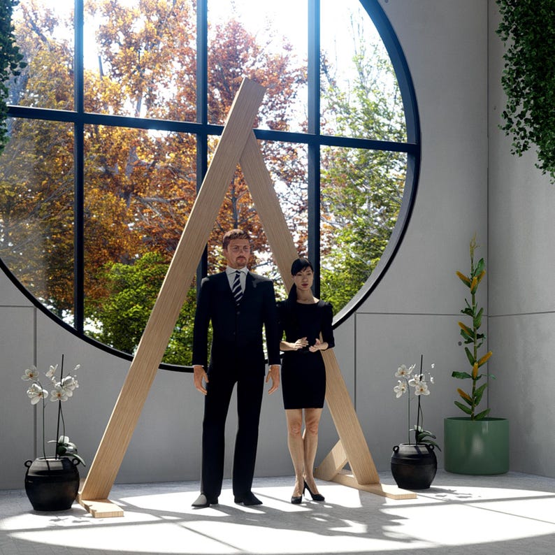 May include: A large, triangular wooden frame stands in front of a circular window. A person in a black suit and a person in a black dress stand between the wooden beams. Two black pots with white orchids and a green plant are placed nearby.