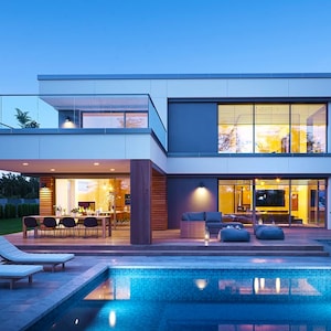 A luxurious villa exterior with elegant architectural details, large windows, and a landscaped backyard. Perfect inspiration for cottage house plans or modern barndominium plans.
