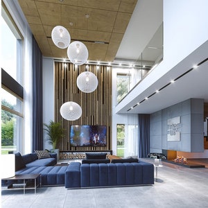 Interior shot of a modern living area featuring a blue sectional sofa, a cozy fireplace, and stylish pendant lighting. Great for those inspired by tiny home plans or scandinavian designs.