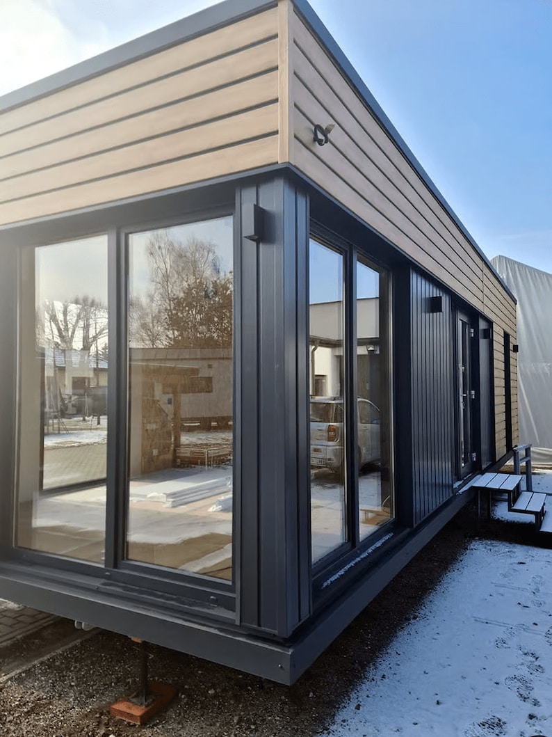 Modern modular house design with large glass windows and wooden cladding, ideal for contemporary house plans, tiny home plans, or barndominium layouts. Perfect for flexible and sustainable living solutions.