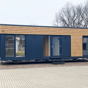 Contemporary modular home with sleek wooden panels and navy accents, designed for flexibility and modern living. Ideal for tiny home plans, townhouse plans, or small cabin layouts with customizable floor plans.