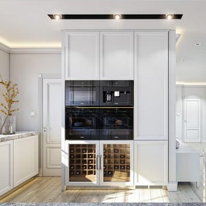 May include: A white kitchen cabinetry unit featuring a central column with two stacked black built-in ovens, a microwave, and a coffee machine, positioned above two glass-fronted wine storage compartments with wooden racks and interior lighting.