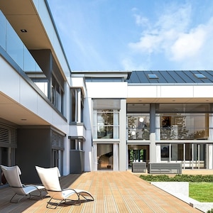 A close-up of a contemporary house's backyard showcasing a spacious patio, glass railings, and sleek architectural lines. Great for modern house plans.