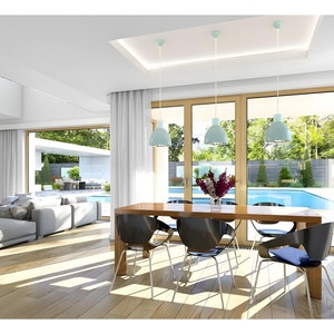 Modern villa interior featuring an open-plan living and dining area with large windows letting in natural light. Offers a pool view, minimalist decor, and elegant wooden furniture, creating a luxurious living experience.