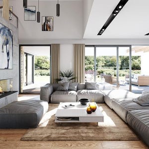 May include: A spacious living room featuring a large gray modular sofa, a low white rectangular coffee table, and a fireplace built into a gray concrete wall. The room includes a brown area rug, wooden flooring, and large glass sliding doors.