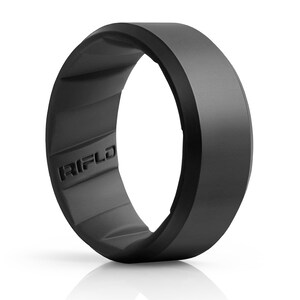 Pode incluir: Um anel preto fosco com uma superf&iacute;cie externa lisa e um interior texturizado com uma s&eacute;rie de ranhuras repetitivas. A palavra RIFLD est&aacute; gravada em letras mai&uacute;sculas na banda interna do anel, que possui um perfil largo e plano.