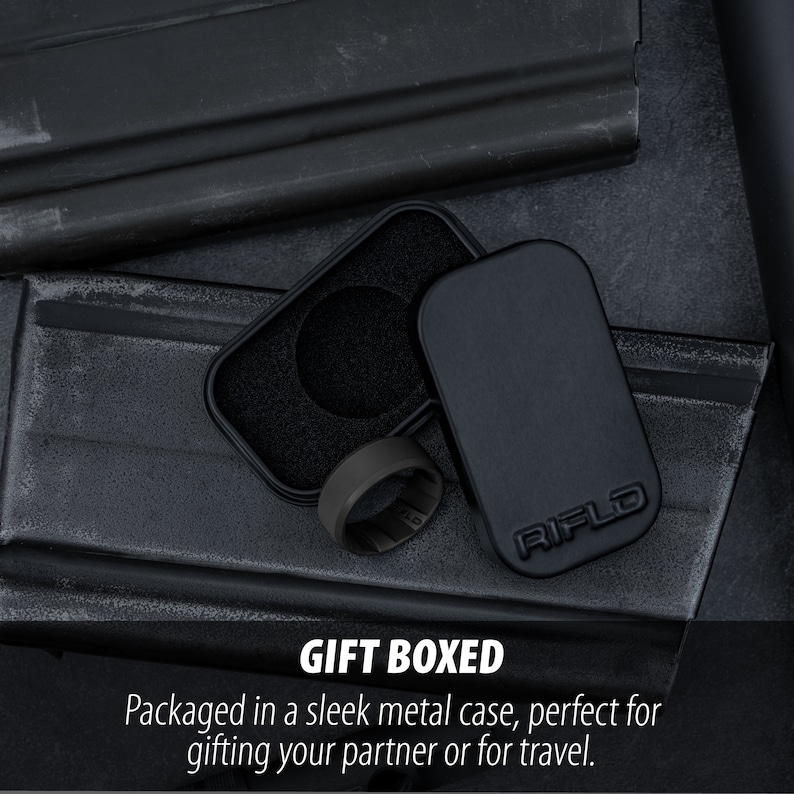 Pode incluir: Um anel preto fosco com uma banda interna texturizada est&aacute; ao lado de uma caixa de metal retangular aberta. A tampa da caixa apresenta o texto em relevo RIFLD. O interior da caixa &eacute; forrado com espuma preta. O texto GIFT BOXED &eacute; vis&iacute;vel.