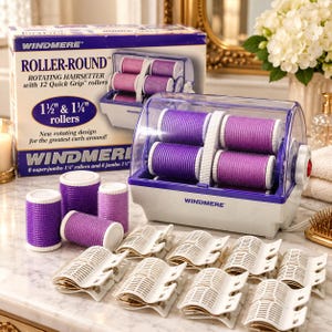 May include: A Windmere Roller-Round rotating hairsetter with a white base and clear lid, containing four purple rollers. Includes eight additional purple rollers and twelve white plastic hair clips, plus the original product box with text.