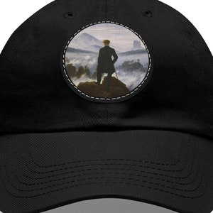 May include: Black baseball cap with a round, white-stitched patch featuring a painting of a man standing on a mountaintop with fog in the background.