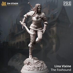 May include: A detailed miniature figurine of a female warrior in a fantasy setting. She is wearing armor and holding a sword and dagger. The figurine is painted in a light gray color and is standing on a rocky base. The text "Lina Vixine The Foxhound" is printed below the figurine.