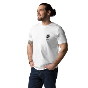 May include: White t-shirt with a small black graphic on the chest. The graphic shows a cartoon character holding a microphone, with the text "The Original" above it. The shirt is made of a soft material.