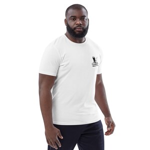 May include: White short-sleeve t-shirt with a small black graphic on the chest. The graphic appears to be a stylized image of a cocktail being prepared. The shirt is made of a soft material.