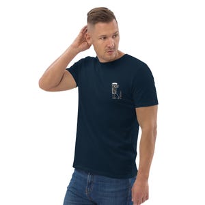 May include: Navy blue t-shirt with a small, minimalist graphic of a golf club, ball, and beer glass. The graphic is in black and white. The shirt is made of a soft material.