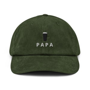May include: A green corduroy baseball cap with white embroidery that says "PAPA" and a small black silhouette of a pint glass above the text.