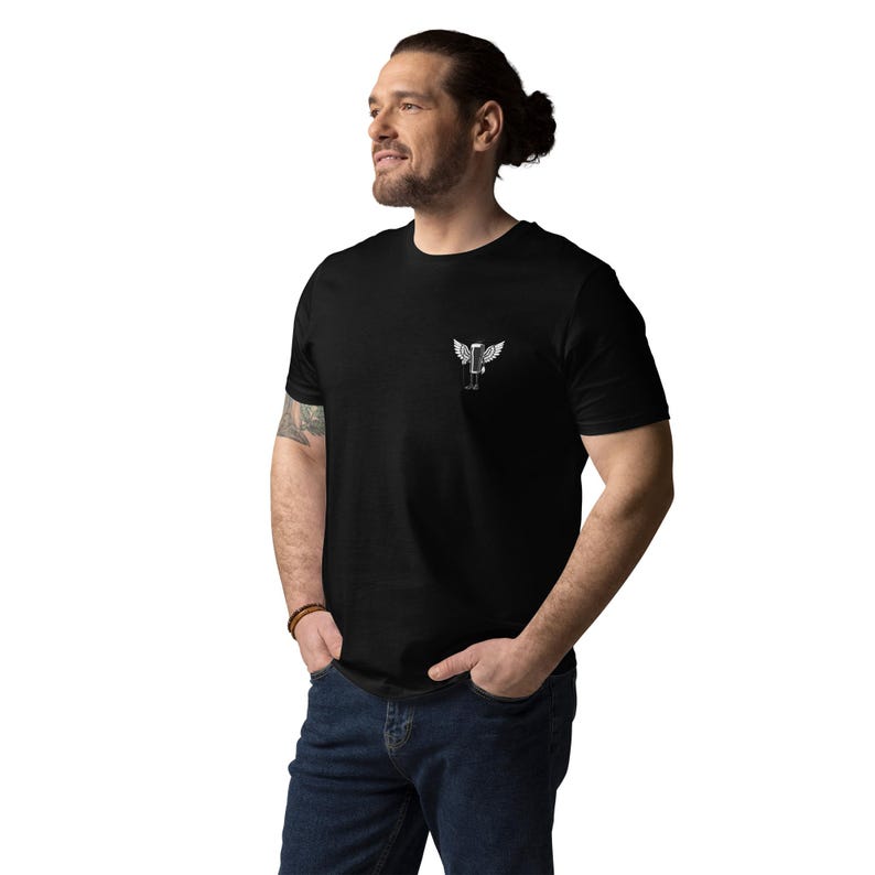 May include: Black t-shirt with a small white graphic of a winged figure on the left chest. The t-shirt is made of a soft material and is being worn by a person in blue jeans.