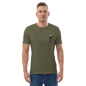 May include: Olive green t-shirt with a small black and white graphic on the left chest. The graphic depicts a person with a golf club and a golf bag. The shirt is made of a soft material.