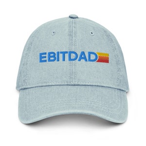 May include: A light blue denim baseball cap with the text "EBITDA" embroidered in blue with a yellow, orange, and red stripe underneath.
