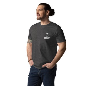 May include: Dark gray t-shirt with a small white graphic on the chest. The graphic appears to be a stylized image of a boat with a person in it. The shirt is made of a soft material and has short sleeves.