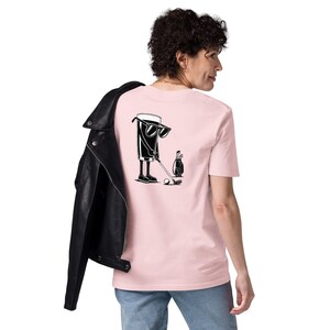 May include: A light pink t-shirt featuring a black and white graphic of a beer glass playing golf, wearing sunglasses, and holding a golf club. A golf bag and ball are also in the image. The person is wearing blue jeans and a black leather jacket.