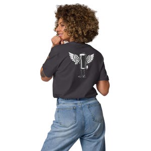May include: Dark gray t-shirt with a white graphic of a beer can with wings and legs. The shirt is made of a soft material and is paired with light blue jeans. The person is facing away from the camera.