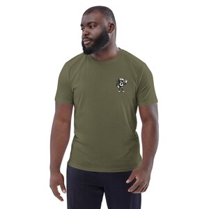 Puede incluir: Camiseta verde oliva con un peque&ntilde;o dibujo animado en el pecho. El gr&aacute;fico representa un personaje con sombrero que levanta la mano. La camiseta est&aacute; hecha de un material suave y tiene un cuello redondo cl&aacute;sico.