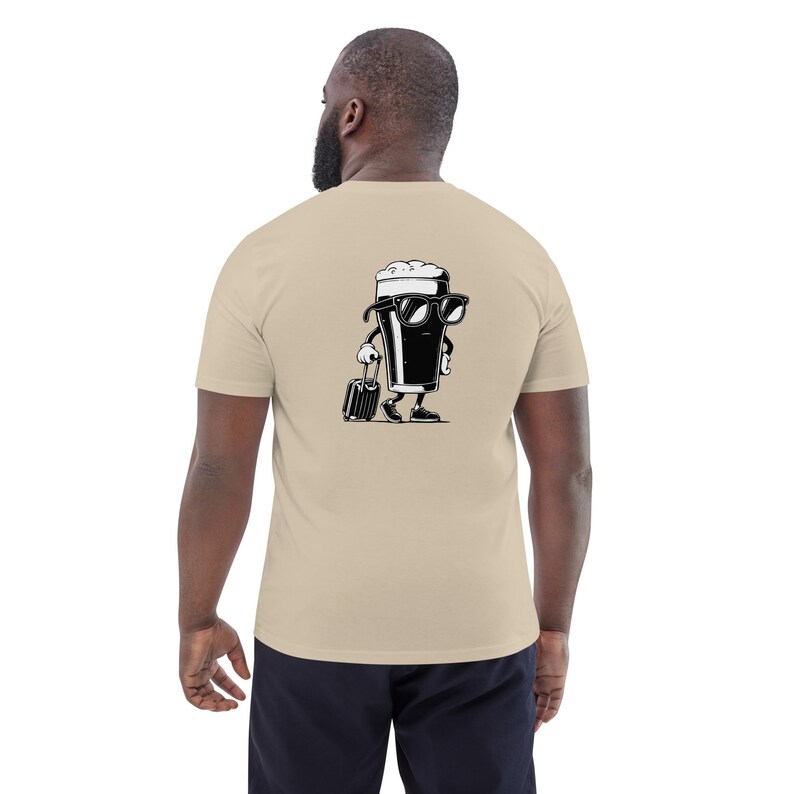 Puede incluir: Camiseta beige con un dise&ntilde;o de vaso de cerveza de dibujos animados en blanco y negro en la espalda. El vaso de cerveza lleva gafas de sol y lleva una maleta. La camiseta est&aacute; hecha de un material suave. El dise&ntilde;o es un gr&aacute;fico divertido con tem&aacute;tica de viajes.