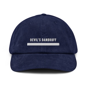 Puede incluir: Una gorra de béisbol de pana azul marino con texto bordado en blanco que dice "DEVIL'S DANDRUFF" y una línea blanca debajo.