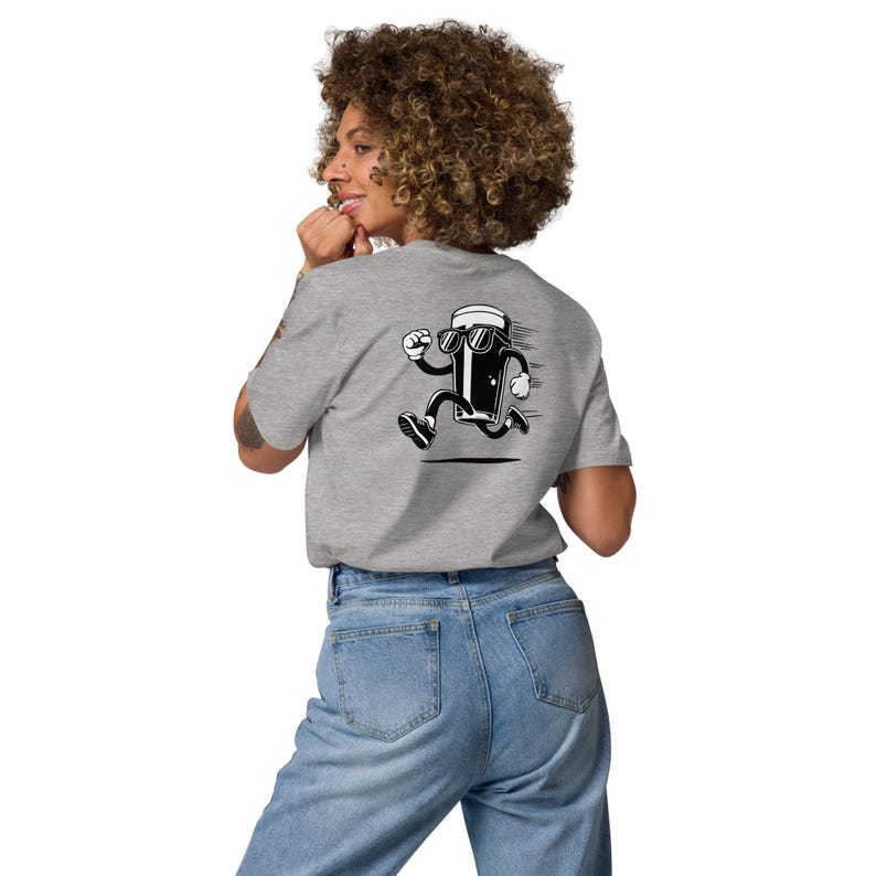 May include: A light gray t-shirt featuring a cartoon image of a running beer mug wearing sunglasses. The graphic is in black and white. The person is wearing blue jeans.