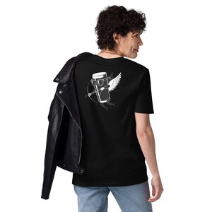 May include: Black t-shirt featuring a white graphic of a beer glass with sunglasses, wings, and a bow and arrow. The shirt is made of a soft material. A black leather jacket is draped over the shoulder.