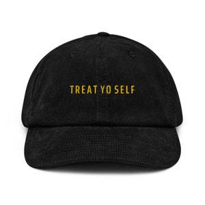 Op de afbeelding: Zwarte corduroy baseballpet met de tekst "TREAT YO SELF" geborduurd in geel.