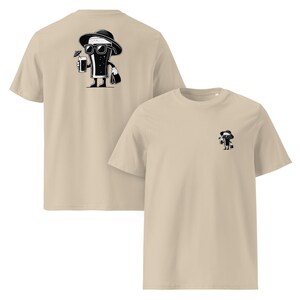 Puede incluir: Dos camisetas beige. Una muestra un dibujo animado en blanco y negro de una bebida con gafas de sol y sombrero, sosteniendo un c&oacute;ctel. La otra camiseta tiene el mismo gr&aacute;fico, pero m&aacute;s peque&ntilde;o, en el pecho.