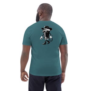 May include: Teal short-sleeve t-shirt with a black and white cartoon cowboy graphic on the back. The graphic depicts a walking glass of stout wearing a cowboy hat, sunglasses, and boots, holding a whip.