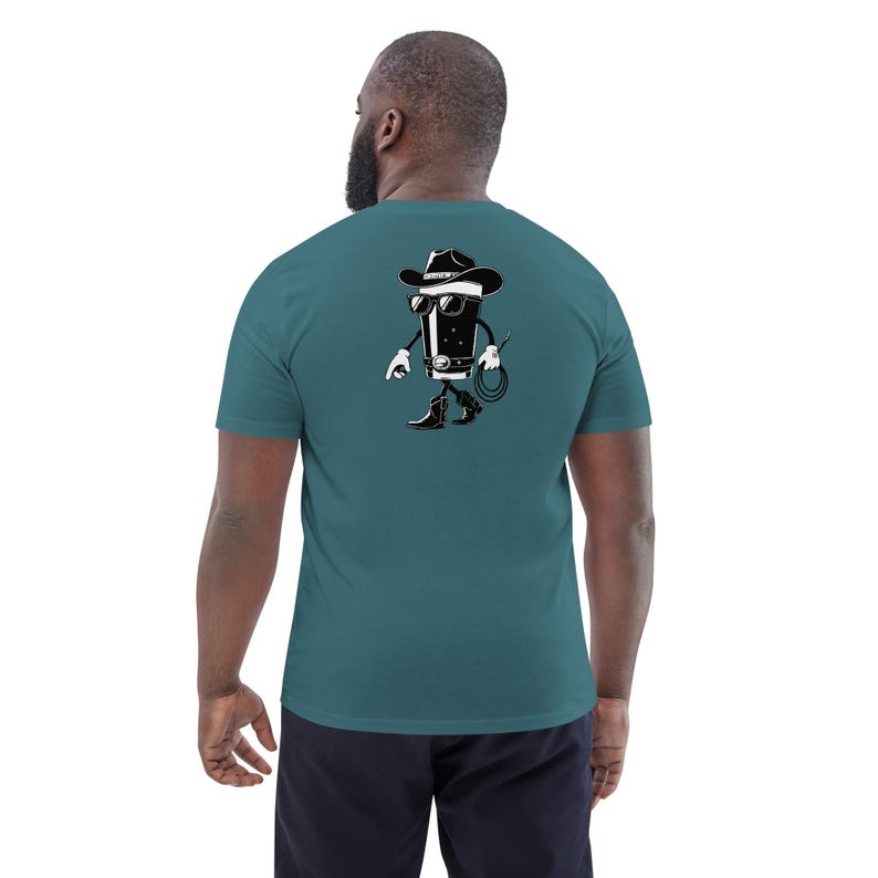 May include: Teal short-sleeve t-shirt with a black and white cartoon cowboy graphic on the back. The graphic depicts a walking glass of stout wearing a cowboy hat, sunglasses, and boots, holding a whip.