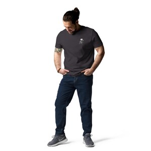 Puede incluir: Una camiseta gris carb&oacute;n con un peque&ntilde;o gr&aacute;fico blanco en la parte superior izquierda del pecho. El gr&aacute;fico es una imagen estilizada de una jarra de cerveza. La persona de la imagen lleva vaqueros azul oscuro y zapatillas deportivas grises.