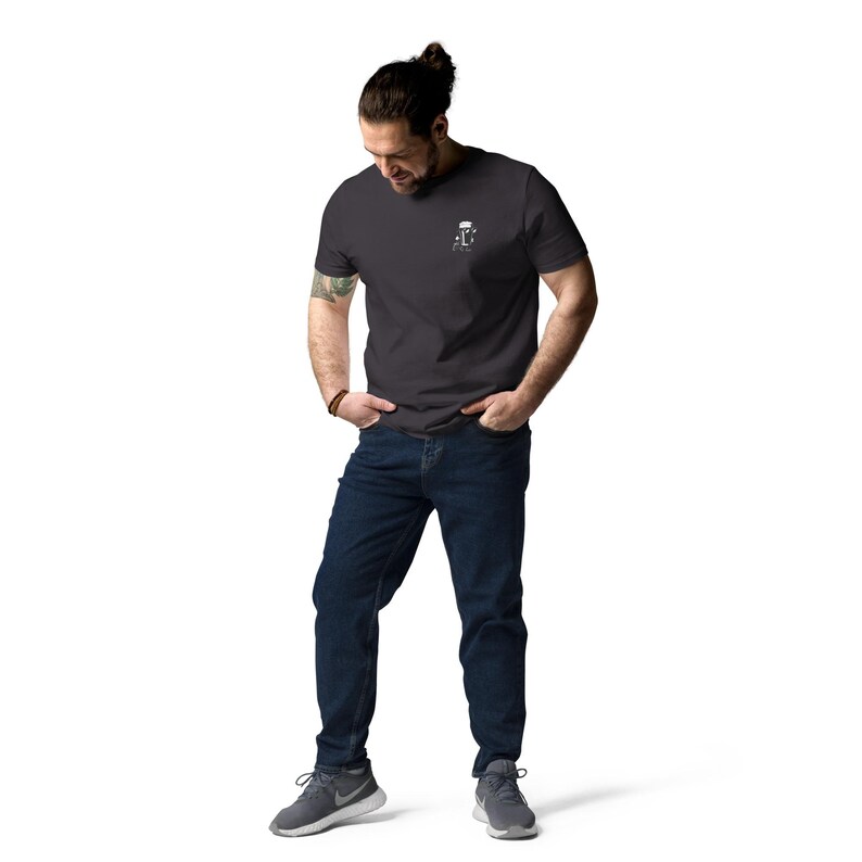 Puede incluir: Una camiseta gris carb&oacute;n con un peque&ntilde;o gr&aacute;fico blanco en la parte superior izquierda del pecho. El gr&aacute;fico es una imagen estilizada de una jarra de cerveza. La persona de la imagen lleva vaqueros azul oscuro y zapatillas deportivas grises.