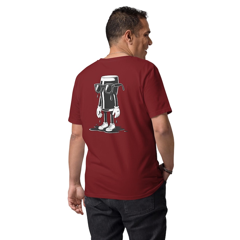 K&ouml;nnte beinhalten: Ein weinrotes T-Shirt mit einer Cartoon-Illustration eines Bierkrugs mit Sonnenbrille, wei&szlig;en Handschuhen und Turnschuhen. Das Bier ist in Schwarz-Wei&szlig; dargestellt und steht in einer Pf&uuml;tze. Das T-Shirt wird von einer Person getragen.