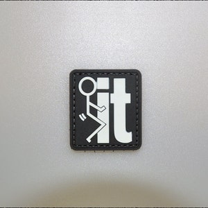 May include: A black square patch featuring white text and a stick figure design. The text reads "it", with the stick figure to the left. The patch has a black border and is square in shape.
