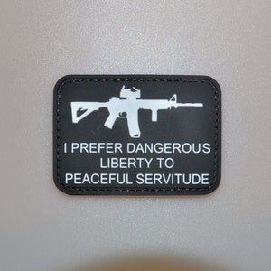 以下が含まれることがあります： 白いライフルシルエットと「I PREFER DANGEROUS LIBERTY TO PEACEFUL SERVITUDE」のテキストが入った黒い長方形のパッチ。 パッチにはステッチされたボーダーがあり、耐久性のある素材で作られている可能性があります。