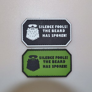 May include: Two rectangular patches. One is black with a white beard graphic and the text "SILENCE FOOLS! THE BEARD HAS SPOKEN!". The other is green with a black beard graphic and the same text.