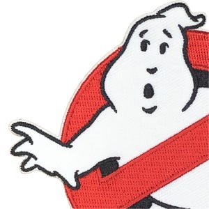 May include: Embroidered patch of the Ghostbusters logo. The patch shows a white ghost-like character with a surprised expression, set against a red background with a black outline. The design is a well-known symbol from the popular film.