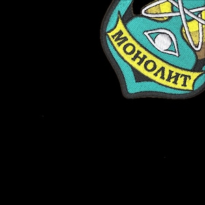 May include: Embroidered patch with a teal and yellow design on a black background. The patch features the word "MOHOЛИТ" in yellow on a teal banner. The design includes geometric shapes and a stylized eye.
