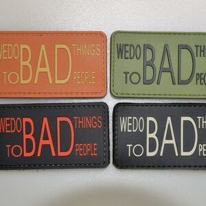 Könnte beinhalten: Vier rechteckige Aufnäher mit dem Text "WE DO BAD THINGS TO BAD PEOPLE". Die Aufnäher sind in Orange, Olivgrün, Schwarz und Dunkelgrau gehalten, mit kontrastierenden Textfarben. Die Aufnäher sind wahrscheinlich für taktische Ausrüstung oder Kleidung bestimmt.