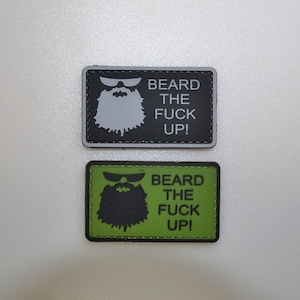 Könnte beinhalten: Zwei rechteckige Aufnäher mit dem Text "BEARD THE FUCK UP!". Ein Aufnäher ist schwarz mit einer weißen Bartgrafik und Text. Der andere ist grün mit einer schwarzen Bartgrafik und Text. Beide Aufnäher haben einen schwarzen Rand.