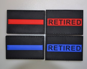 May include: Four black rectangular patches with stitched edges. Two have a red stripe or the word "RETIRED" in red. The other two have a blue stripe or the word "RETIRED" in blue. Patches are likely for uniforms.