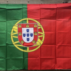 Puede incluir: Bandera rectangular de Portugal, con una franja vertical verde en el lado del asta y una franja vertical roja en el lado del vuelo. El escudo de armas portugués está centrado, con una esfera armilar amarilla y un escudo.